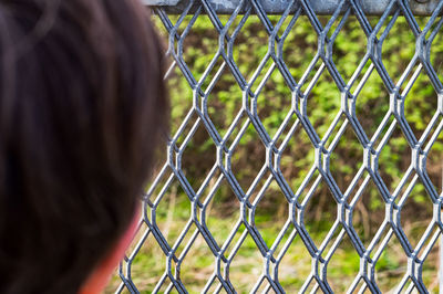 Close-up portrait of man seen through chainlink fence