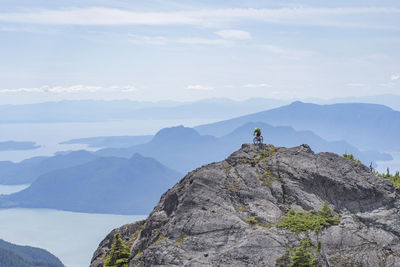 Man riding bicycle on mountain against sky