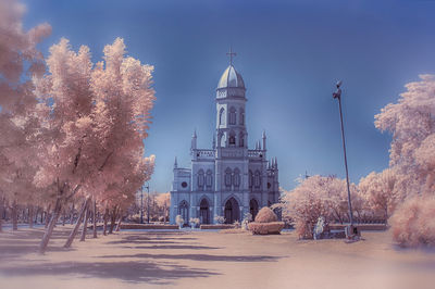 View of building and trees against sky in city