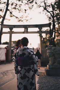 Rear view of women standing outdoors during sunset