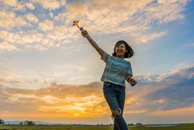 Low angle view of woman standing against sky during sunset