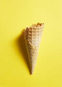 Close-up of ice cream cone against yellow background