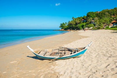 Tropical landscape with boat at sand beach, blue sky and turquoise sea