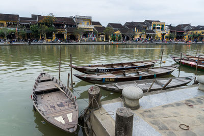 Boats moored in lake with city in background
