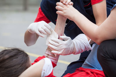 Midsection of people holding injured woman on street