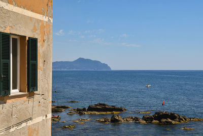 Seascape with an old house, rocks and the promontory of portofino on the sea horizon, boccadasse