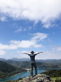 Rear view of man with arms outstretched standing on mountain