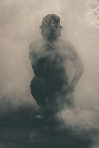 Full length of man crouching amidst smoke