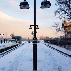 Snow covered railroad tracks against sky during winter