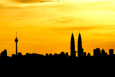 Silhouette petronas tower and kuala lumpur tower against orange sky