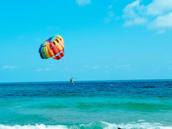 People paragliding in sea against sky