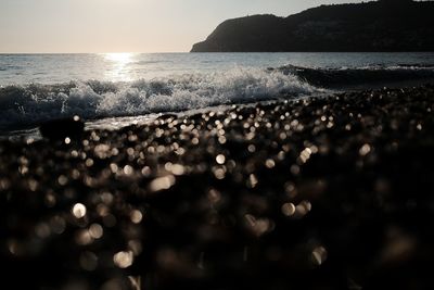 Close-up of sea shore against sky during sunset