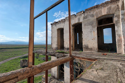 Old abandoned house on field against sky