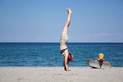 Upside down image of woman exercising on sand at beach