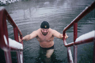 Shirtless man wading in lake