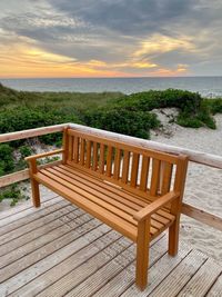 Wooden chair on beach against sky