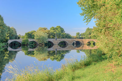 Arch bridge over lake against clear blue sky