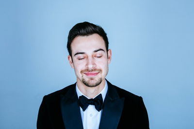 Smiling well-dressed young man against blue background