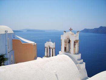 Two white bell towers against the backdrop of sea and caldera in oia on island of santorini, greece