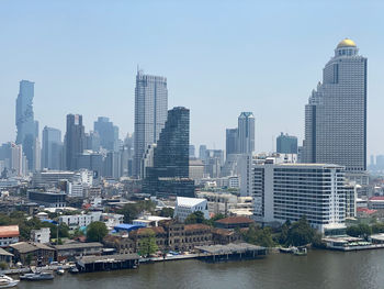 Buildings by river against sky in city