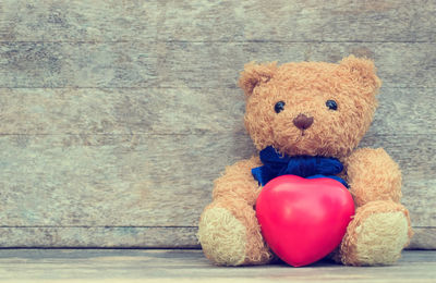 Close-up of teddy bear with heart shape against wall