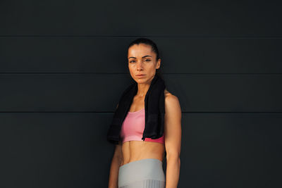 Portrait of young woman standing against wall