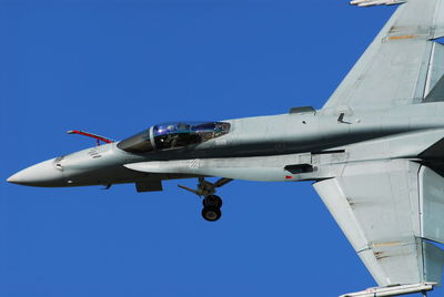 Low angle view of airplane flying against clear blue sky