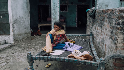 Woman sitting in front of built structure