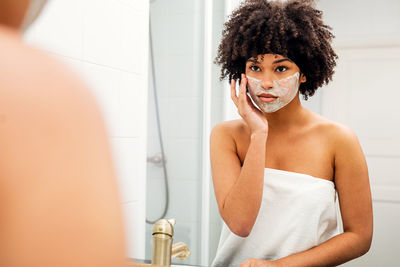 Young woman with arms raised in bathroom