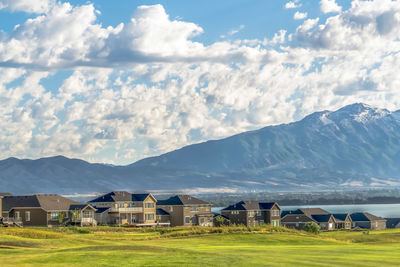 Houses on field by mountains against sky