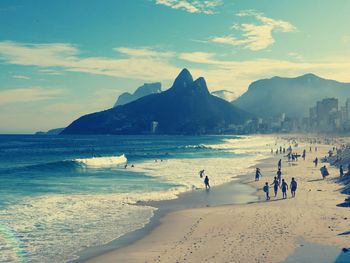 Panoramic view of people on beach against sky