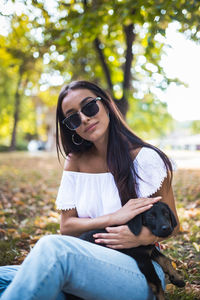 Young woman wearing sunglasses and dog against plants