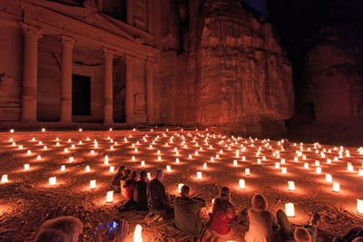 Illuminated candles glowing against temple at night