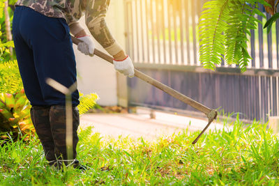 Low section of man cleaning grass with shovel in lawn