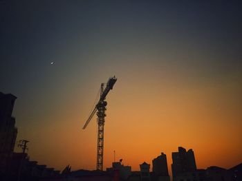 Low angle view of silhouette crane against sky during sunset