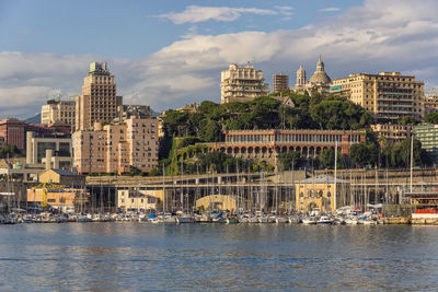 Buildings by river against sky