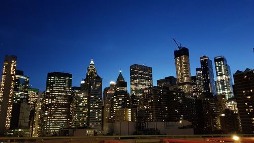 Illuminated buildings against clear blue sky at night