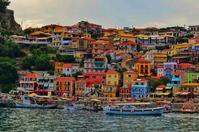 Sailboats moored in sea against buildings in city