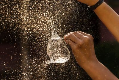 Cropped hands bursting water balloon