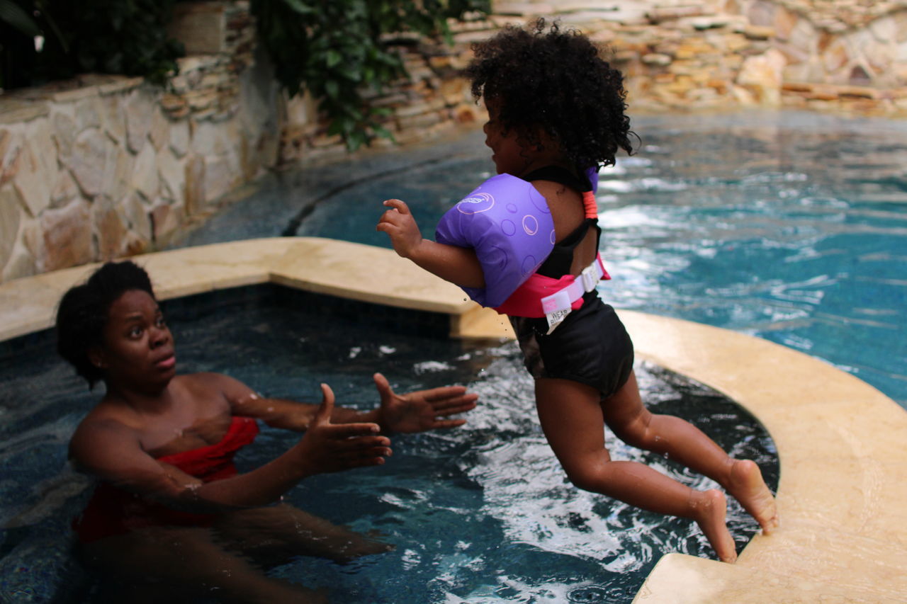 FULL LENGTH OF HAPPY FRIENDS IN SWIMMING POOL AT RIVERBANK