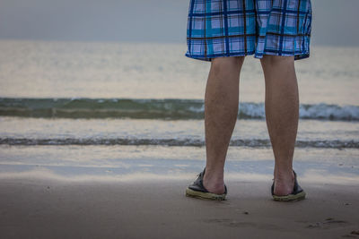 Low section of man standing on beach