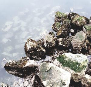 Stack of stones in sea against sky