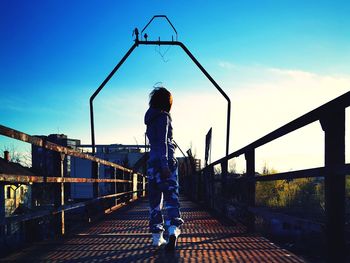 Rear view of man standing on bridge against sky