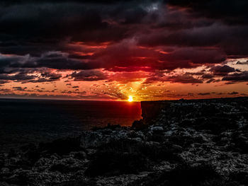 Scenic view of sea against dramatic sky during sunset