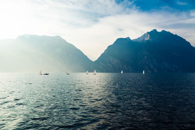 Scenic view of sea by mountains against sky