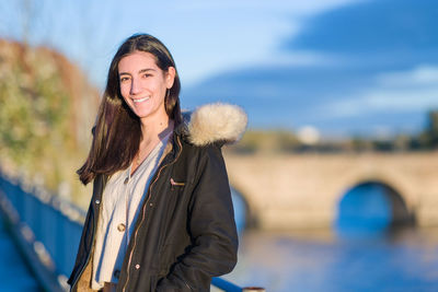 Portrait of young woman standing against sky