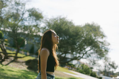 Woman looking away while standing at park