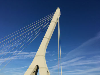 Low angle view of suspension bridge against blue sky