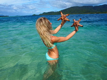 Woman holding starfish in sea