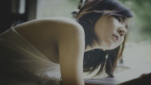 Young woman looking away while sitting on floor